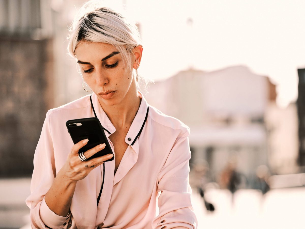 Symbolbild einer aufs Smartphone schauenden Frau