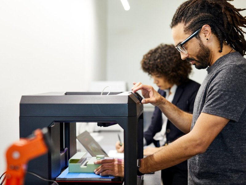 Mann und Frau an einem 3D-Drucker.