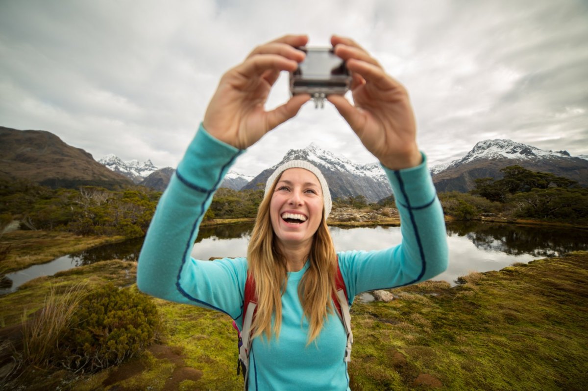 Frau macht in den Bergen ein Selfie mit einer Action-Cam.