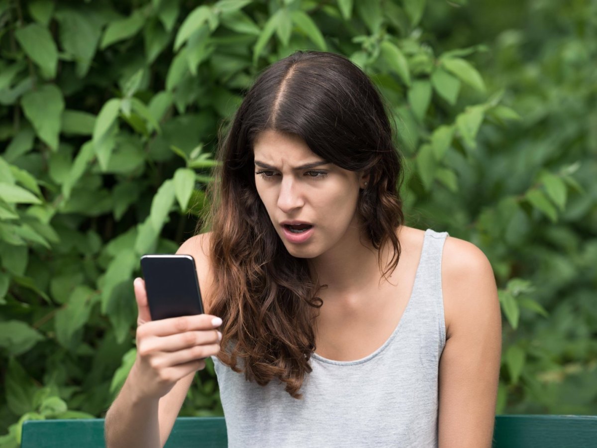 Frau regt sich über ihr Smartphone/ ihren Handy-Akku auf.