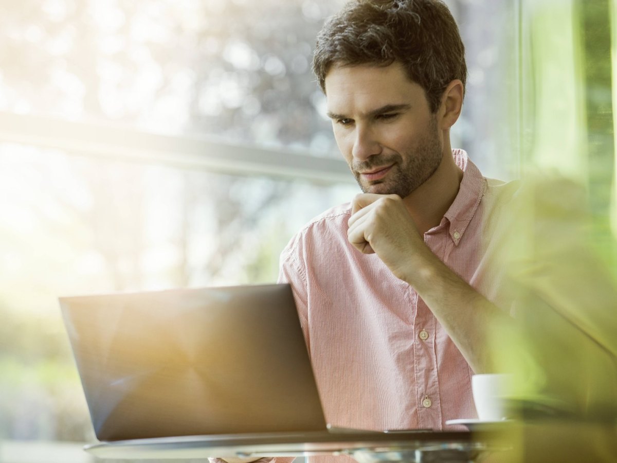 Mann sitzt vor dem Laptop und shoppt online bei Amazon.