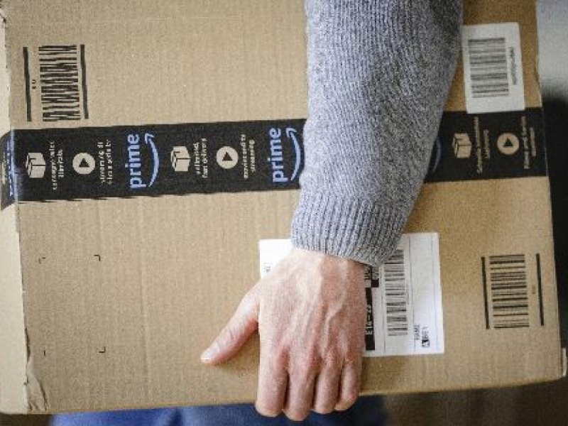 Mann mit Amazon Prime Paket in der Hand.