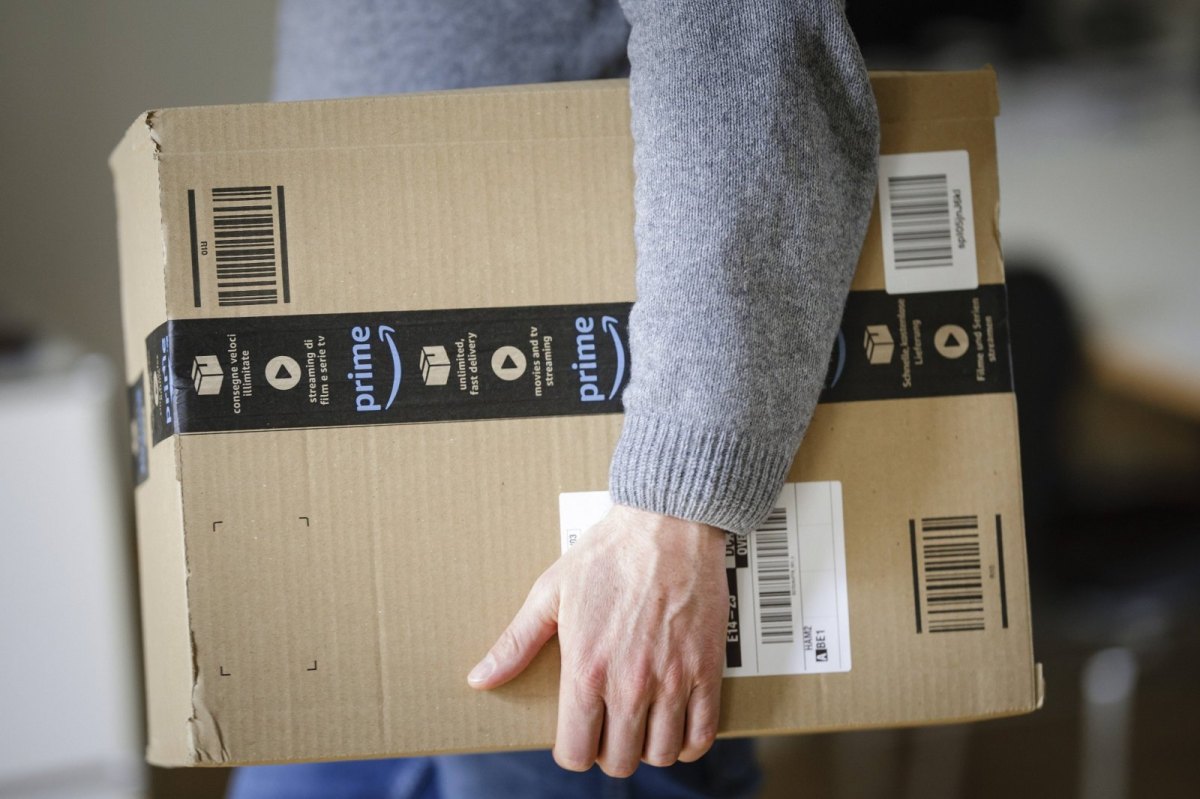 Mann trägt ein Amazon-Paket unter dem Arm