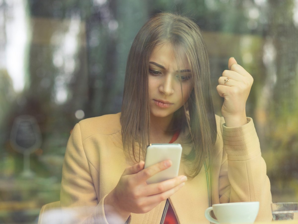 Frau schaut irritiert auf ihr Handy.