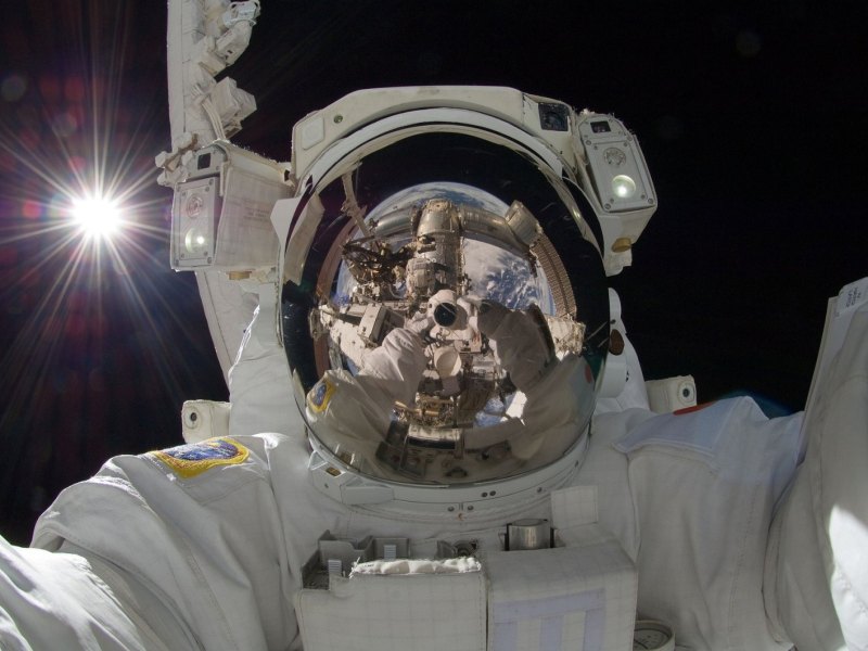 Ein Astronaut im Weltall schaut in die Kamera.
