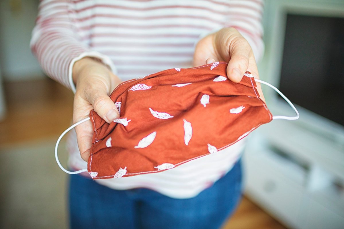 Frau hält DIY-Mundschutz in die Kamera