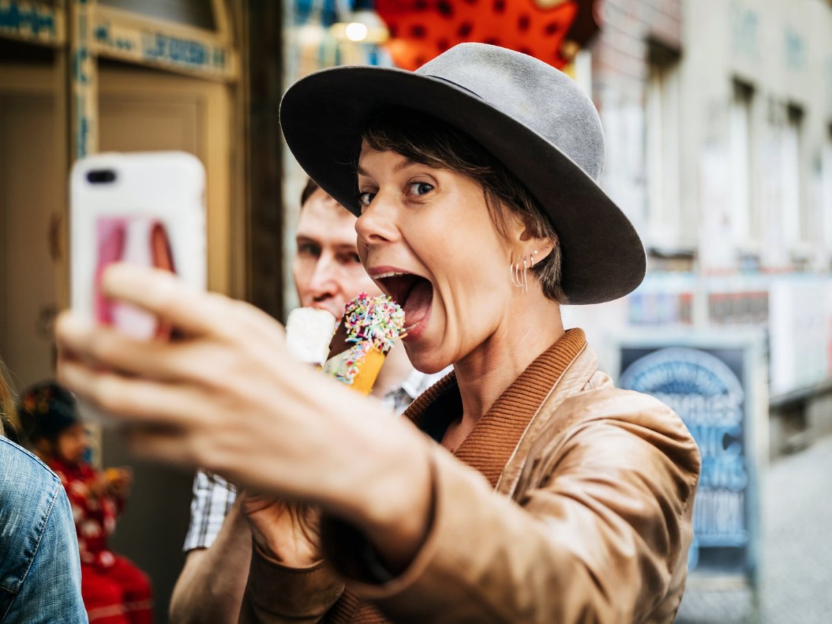 Frau macht Foto von sich mit einem Handy.