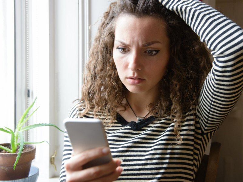 Frau guckt schockiert auf ihr Handy