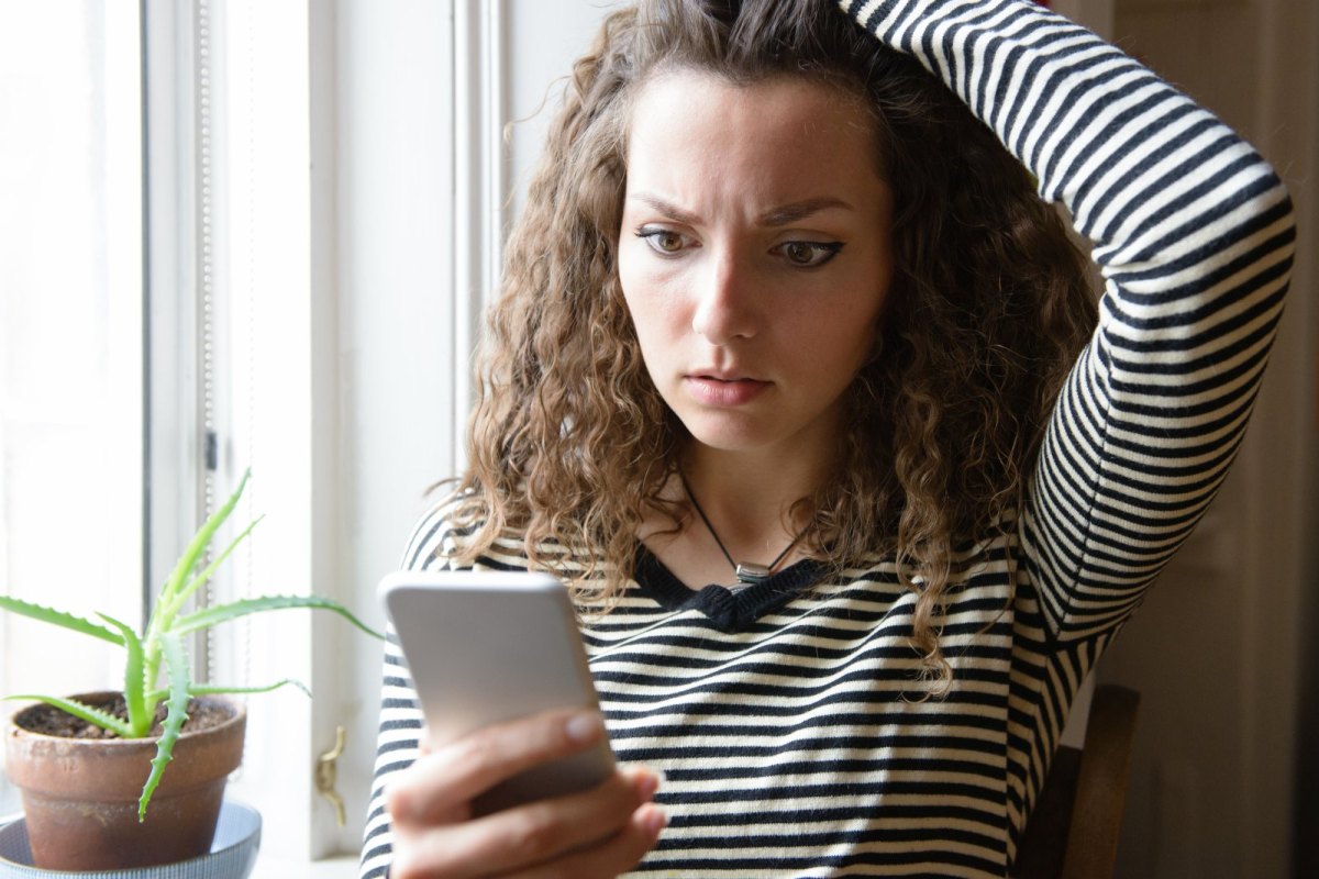 Frau guckt schockiert auf ihr Handy