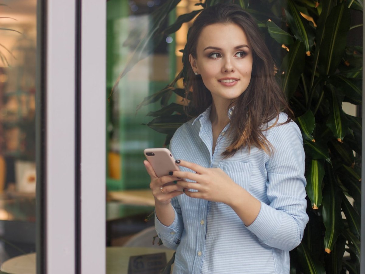 Frau hält Smartphone in der Hand und lacht.