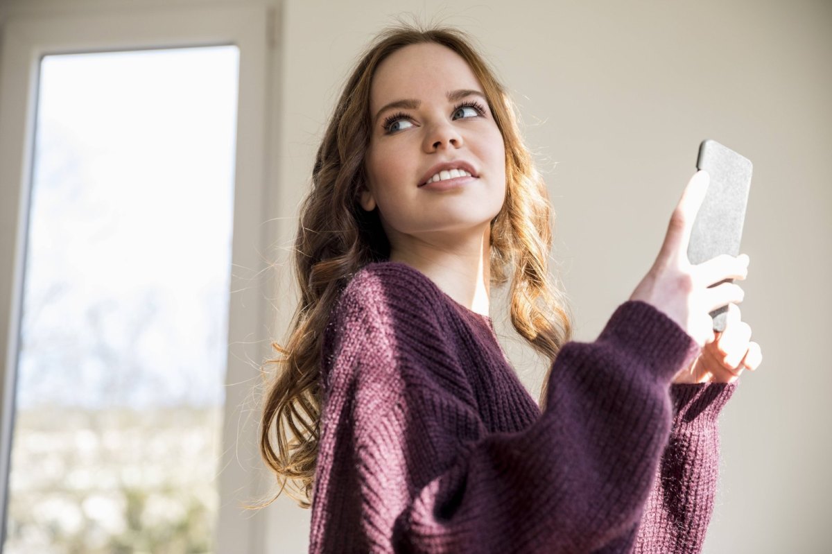 Frau hält ihr Handy in der Hand.