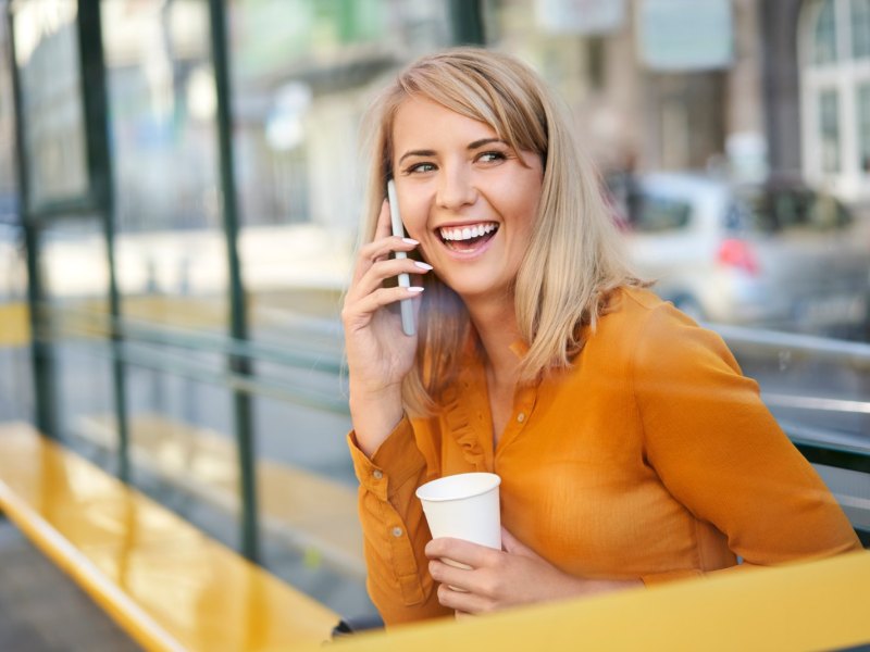 Frau telefoniert lachend mit ihrem Handy.