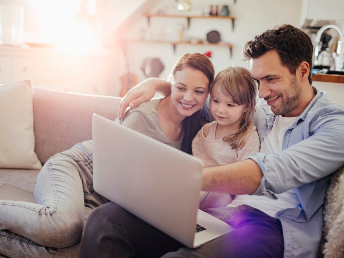 Familie sitzt vor einem Laptop.