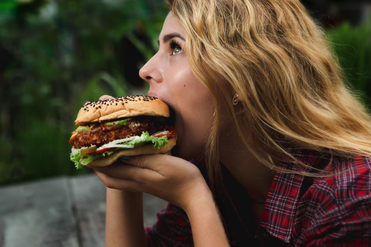 Frau beißt genüsslich in Burger.