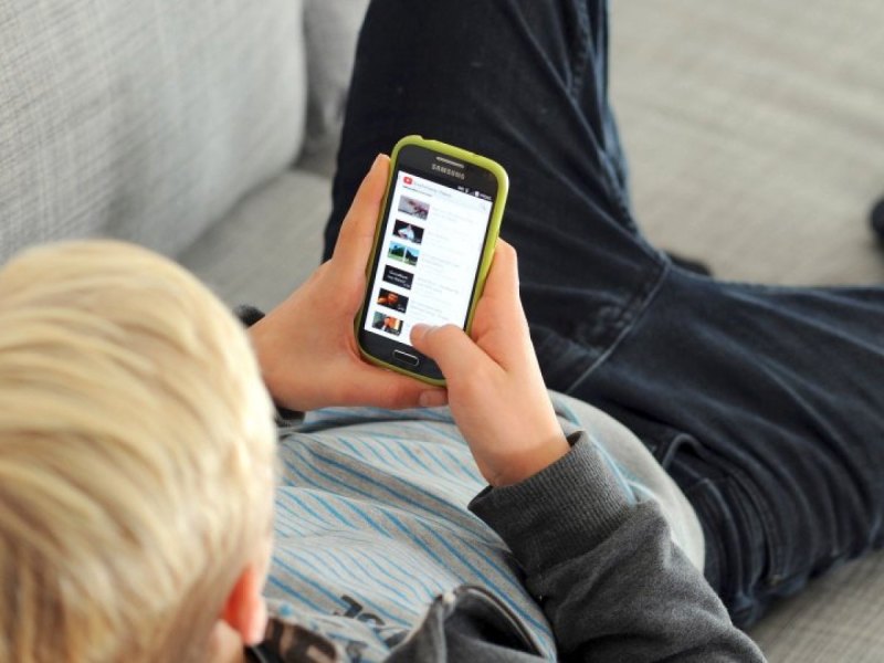 Junge mit Smartphone auf dem Sofa