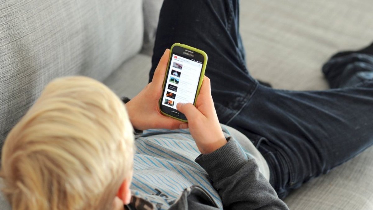 Junge mit Smartphone auf dem Sofa