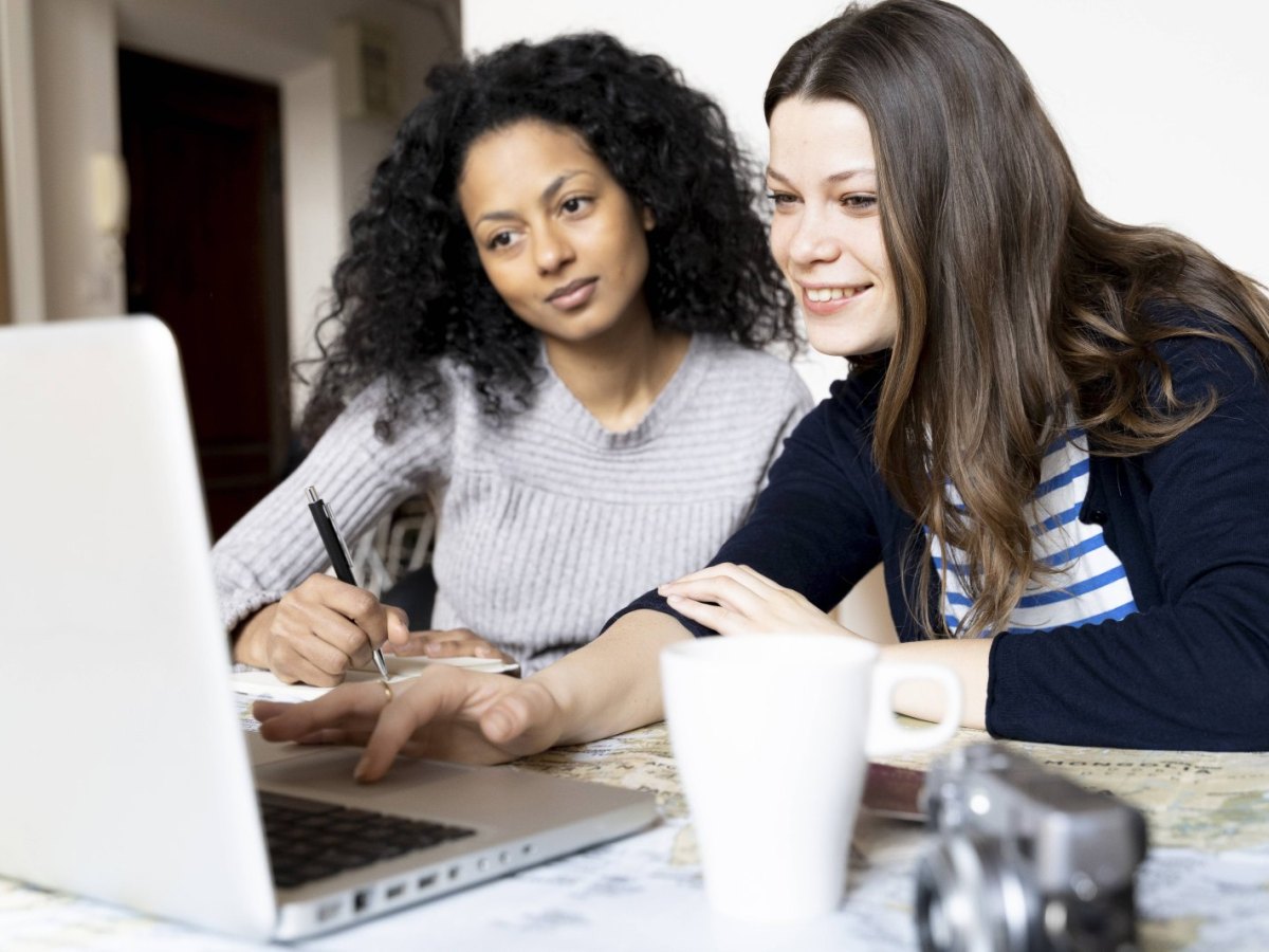 Zwei Frauen bucen eine Reise am Laptop.