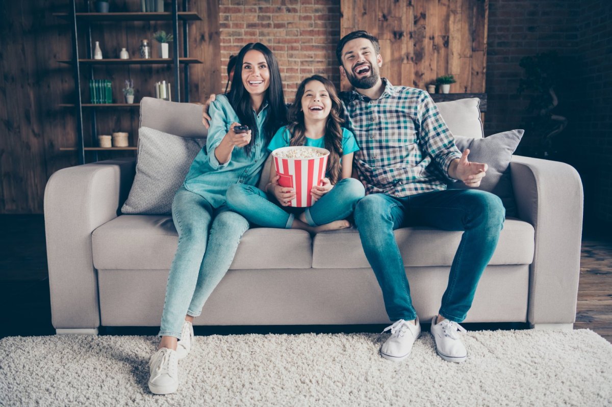 Familie sitzt mit Popcorn vor dem Fernseher.