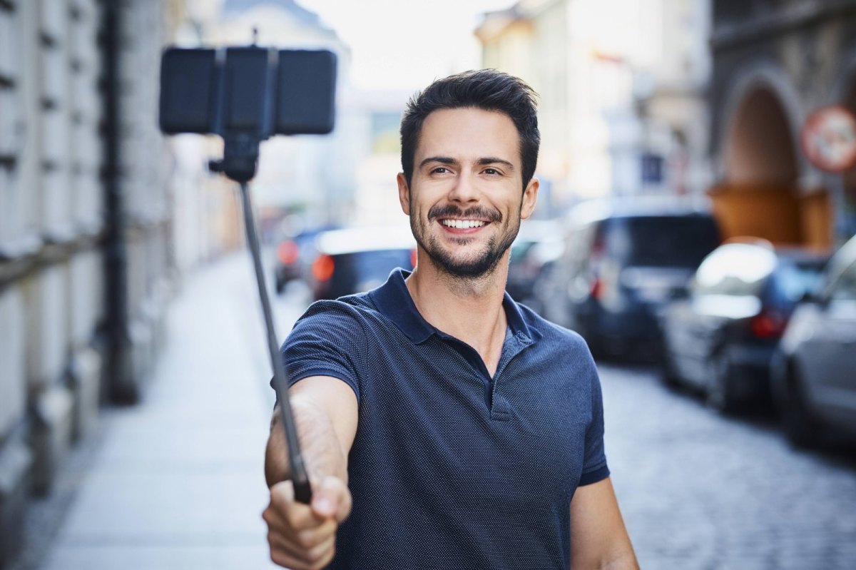 Mann schießt Bild mit Smartphone am Selfie-Stick