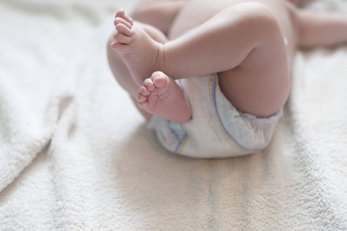 Ein Baby trägt eine Windel und streckt die Füße in die Höhe.