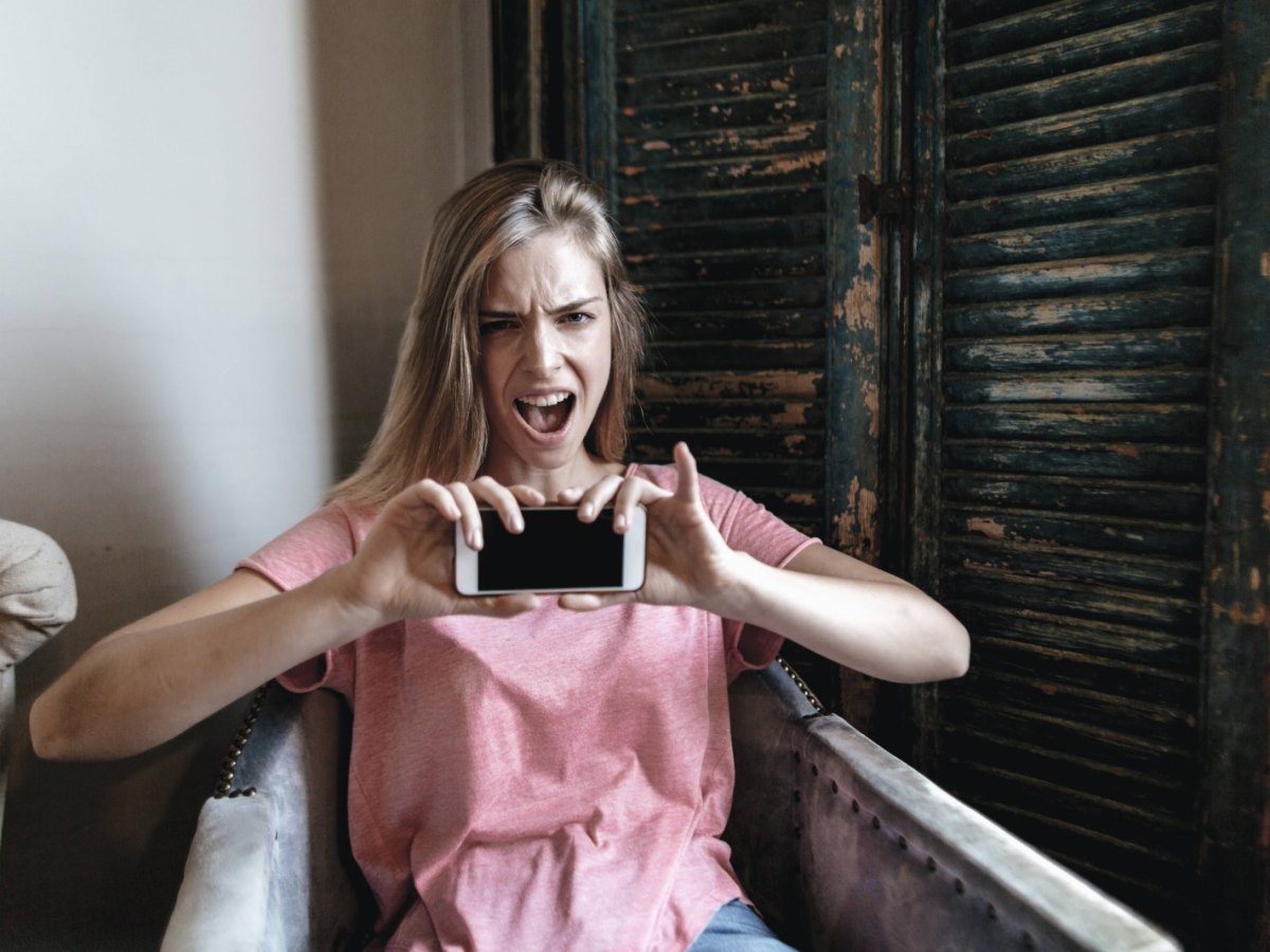 Eine Frau ist wütend und hält ein Smartphone in der Hand.