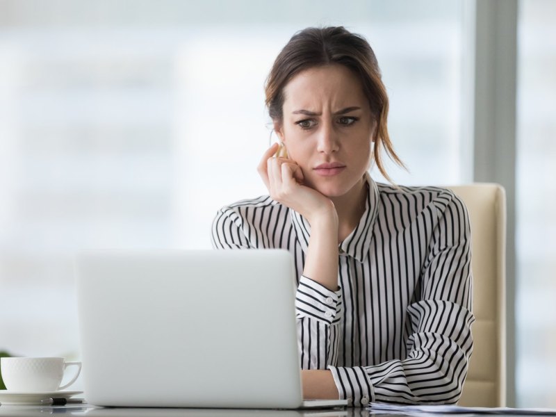 Frau sitzt skeptisch guckend vor einem Computer