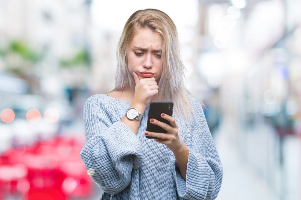 Frau schaut skeptisch auf ihr Handy