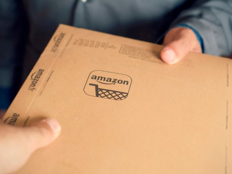 Mann hält Amazon-Paket in der Hand