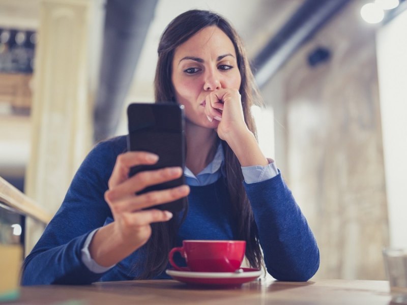 Frau schaut misstrauisch auf ihr Handy.