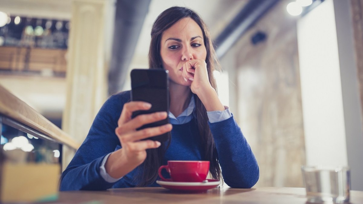 Frau schaut misstrauisch auf ihr Handy.