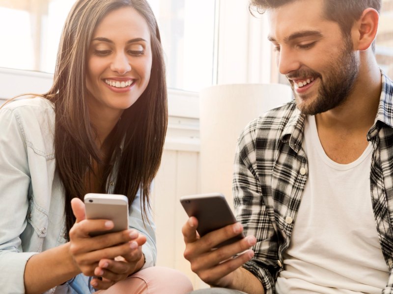 Ein Mann und eine Frau schauen glücklich auf ihr Handy