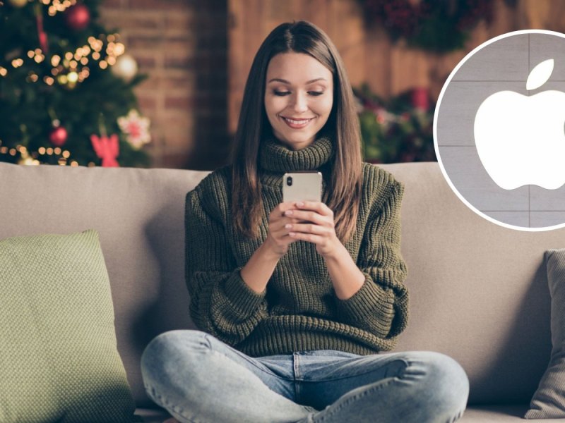 Frau mit Handy auf dem Sofa. Hinter ihr ein Weihnachtsbaum