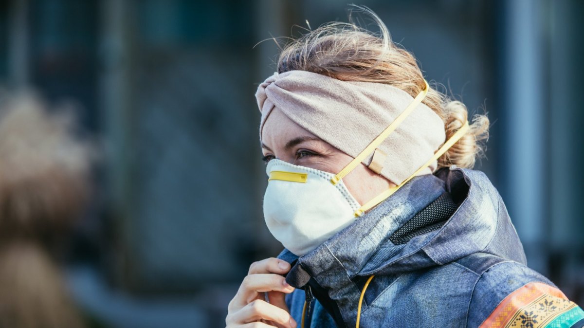 Frau mit Maske in Winterjacke