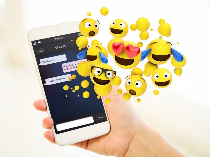 Emojis kommen aus dem Bildschirm eines Handys.