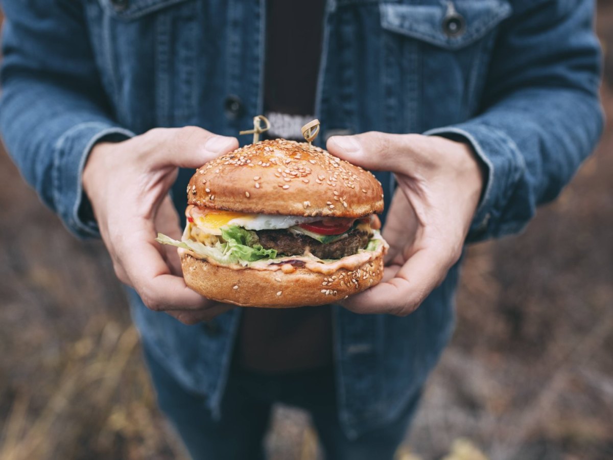 Mann hält Burger in die Kamera