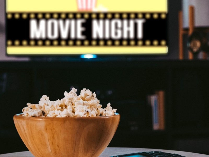 Popcorn auf dem Tisch vor dem TV mit Movie Night-Aufschrift.