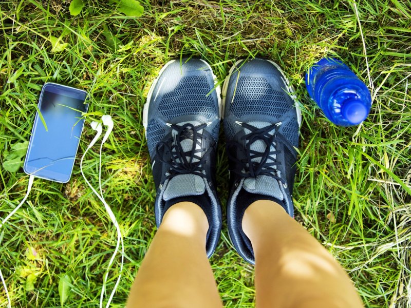 Person mit Sportschuhe steht im Gras