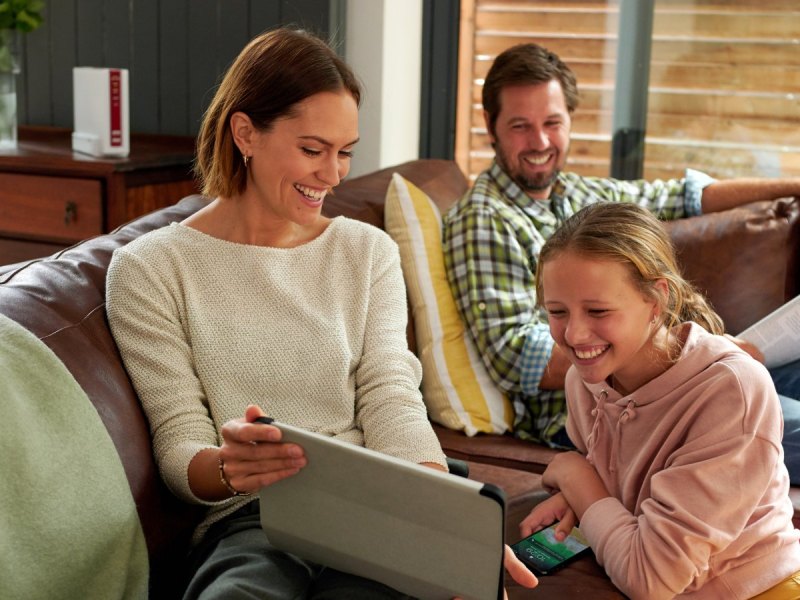 Familie im Wohnzimmer mit Router im Hintergrund.