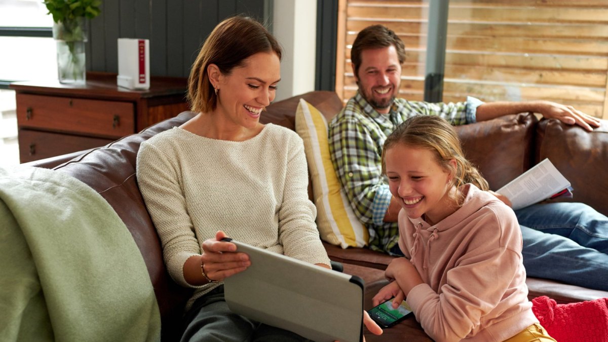 Familie im Wohnzimmer mit Router im Hintergrund.