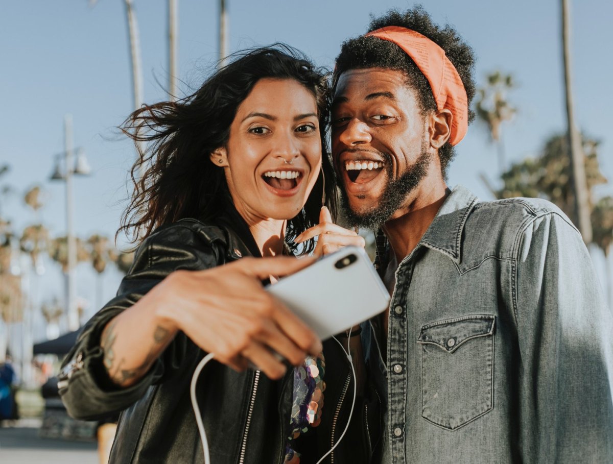 Zwei junge Menschen machen ein Selfie auf einer Strandpromenade.