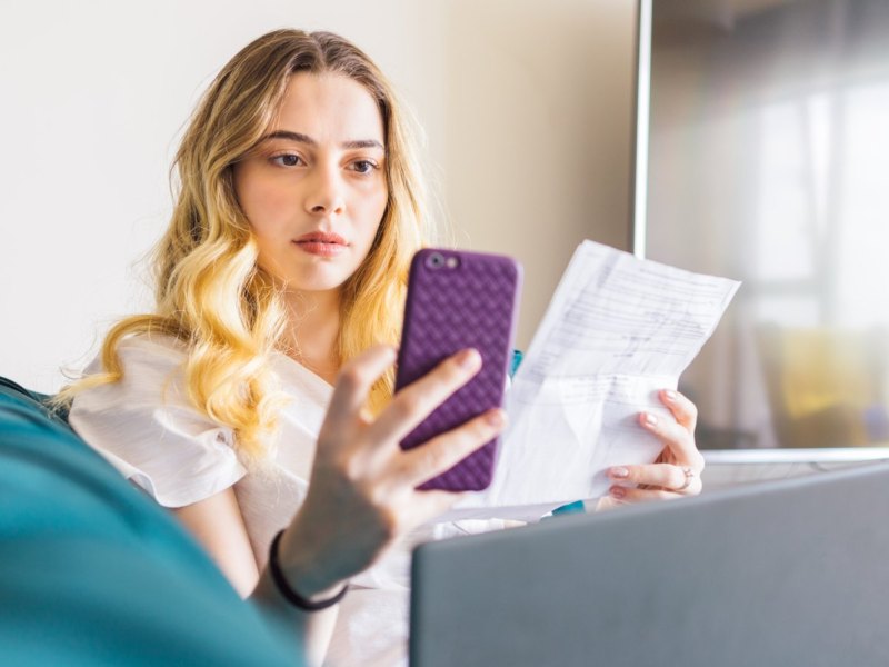 Frau mit Rechnung und Handy in der Hand