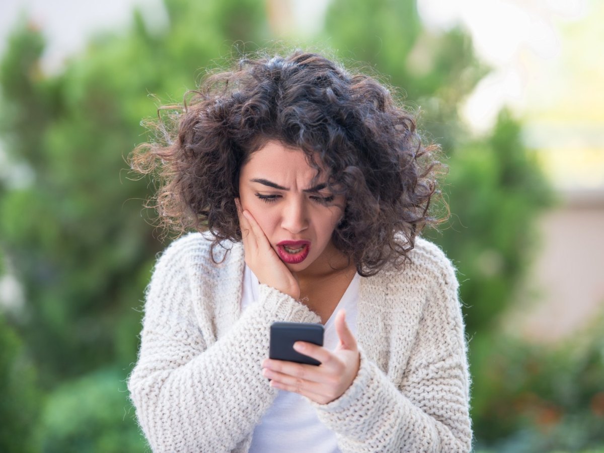 Frau schaut äußerst besorgt auf ihr Handy.