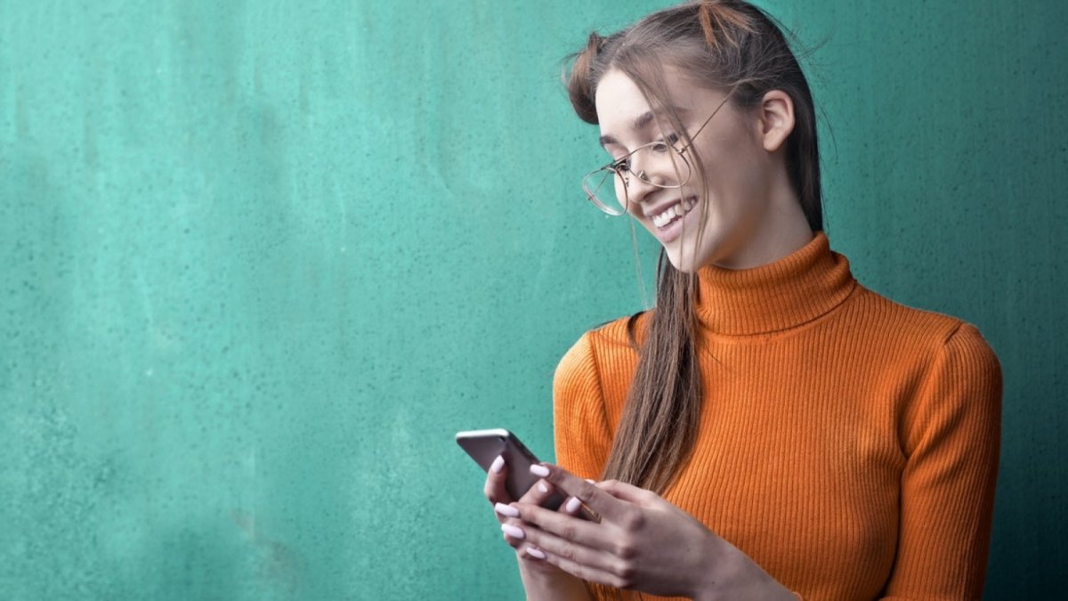 Eine Frau schaut auf ihr Smartphone in ihren Händen.