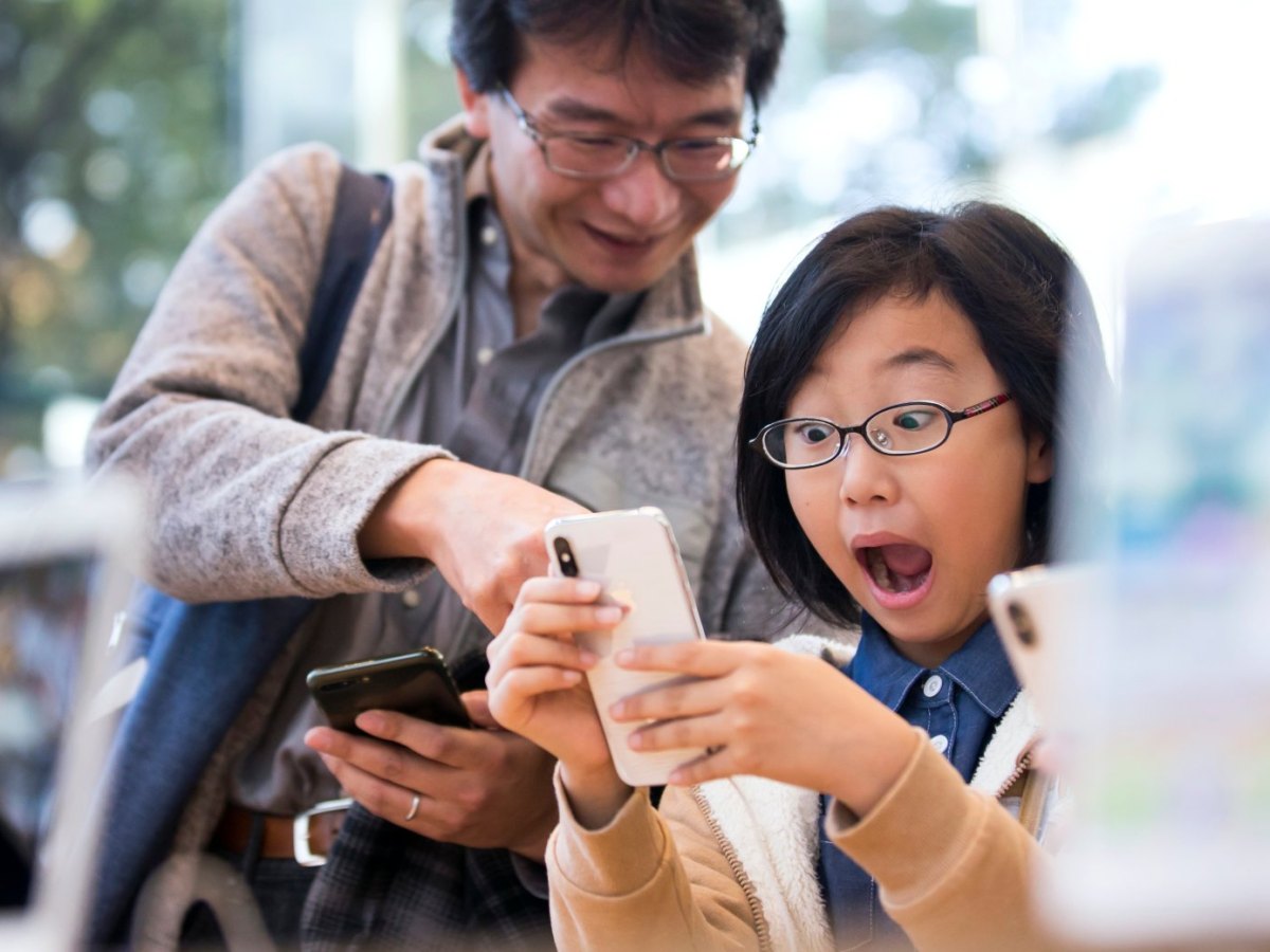 Frau hält iPhone X in der Hand und macht begeistertes Gesicht.