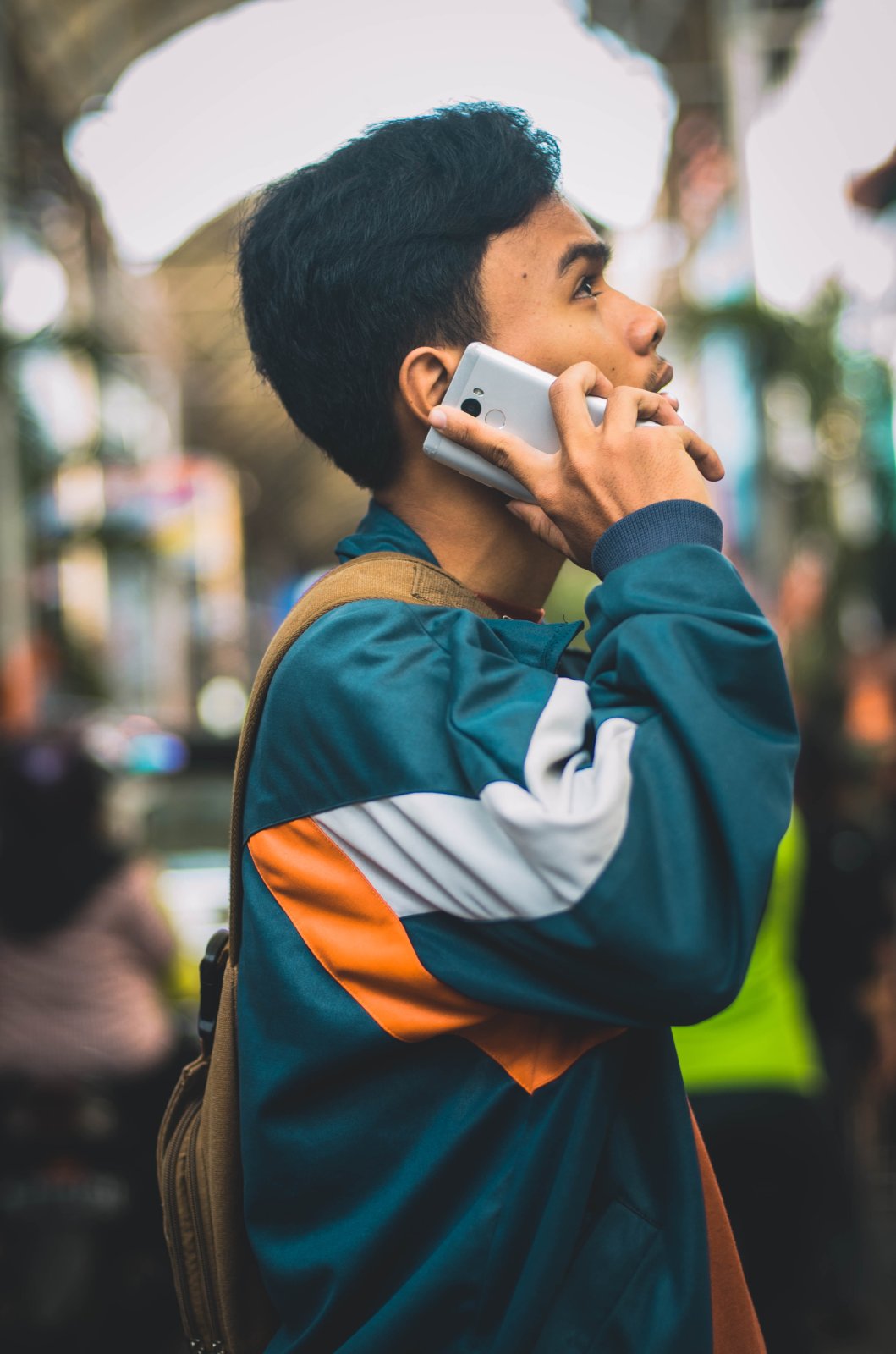 Junger Mann in Trainingsjacke telefoniert mit seinem Android-Smartphone