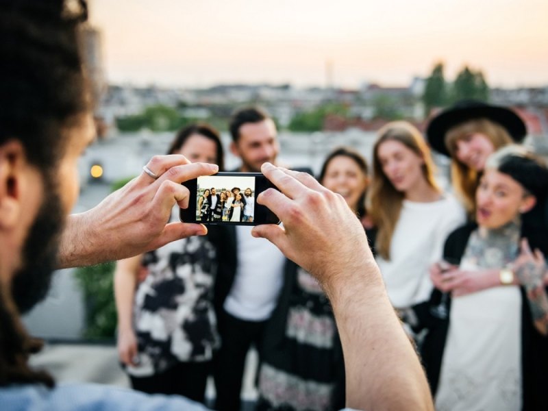 Mann fotografiert mehrere Menschen.