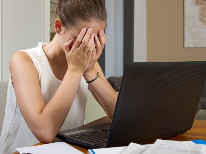 frau verzweifelt vor laptop weil er nicht angeht