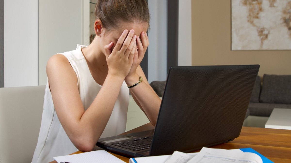 frau verzweifelt vor laptop weil er nicht angeht