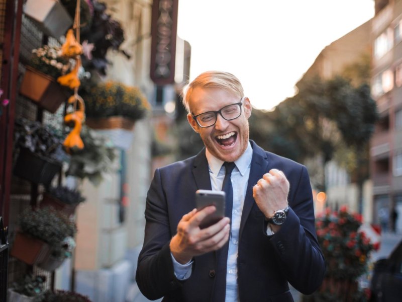 Ein glücklicher Mann mit Handy in der Hand