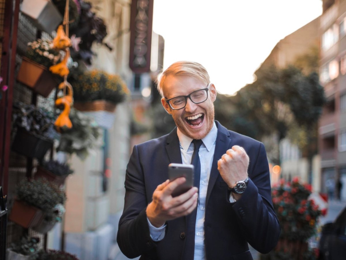 Ein glücklicher Mann mit Handy in der Hand